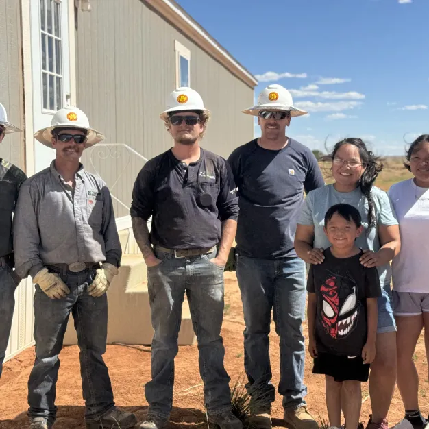 Mountain Parks Electric linemen stand with Navajo family who received power through the Light Up Navajo project.